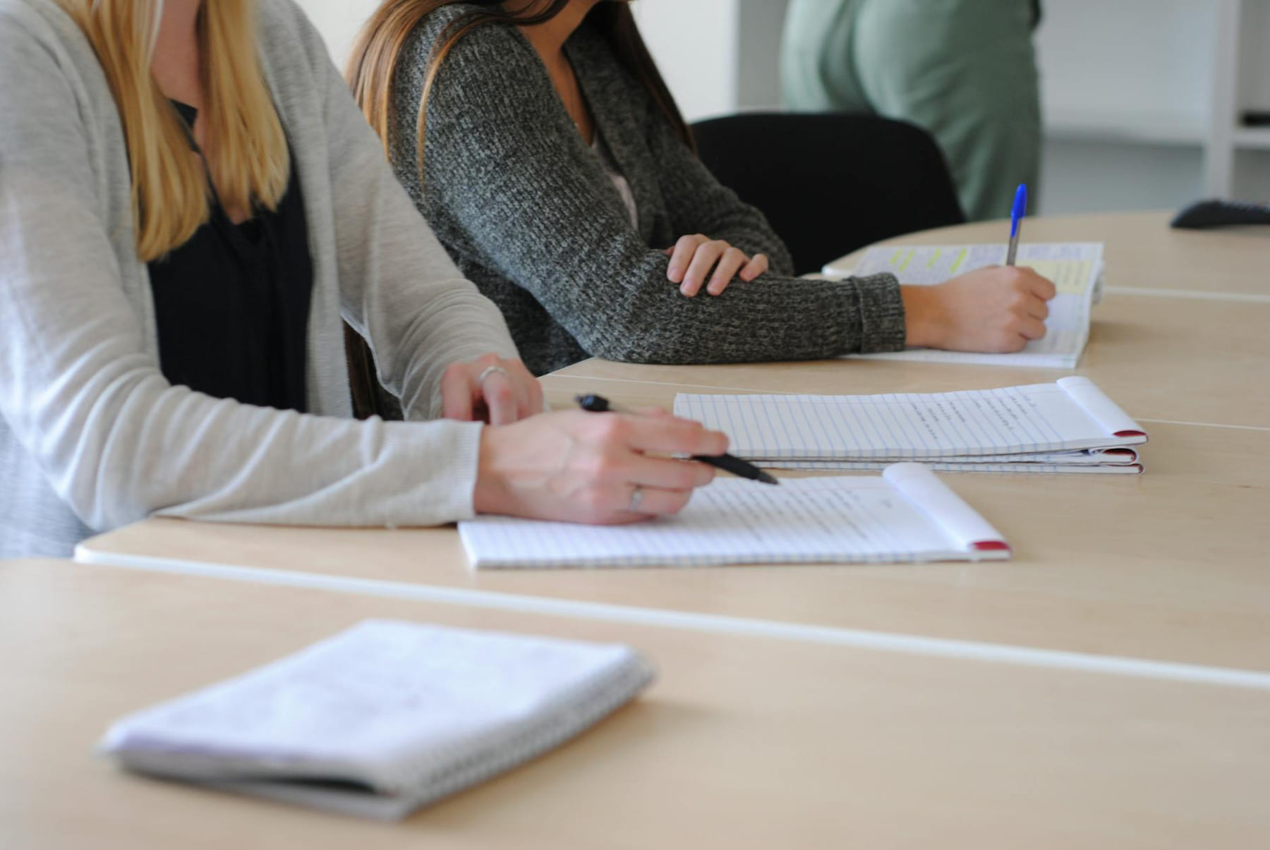Group of students writing notes at a meeting in a well-lit classroom. on The Course Compass