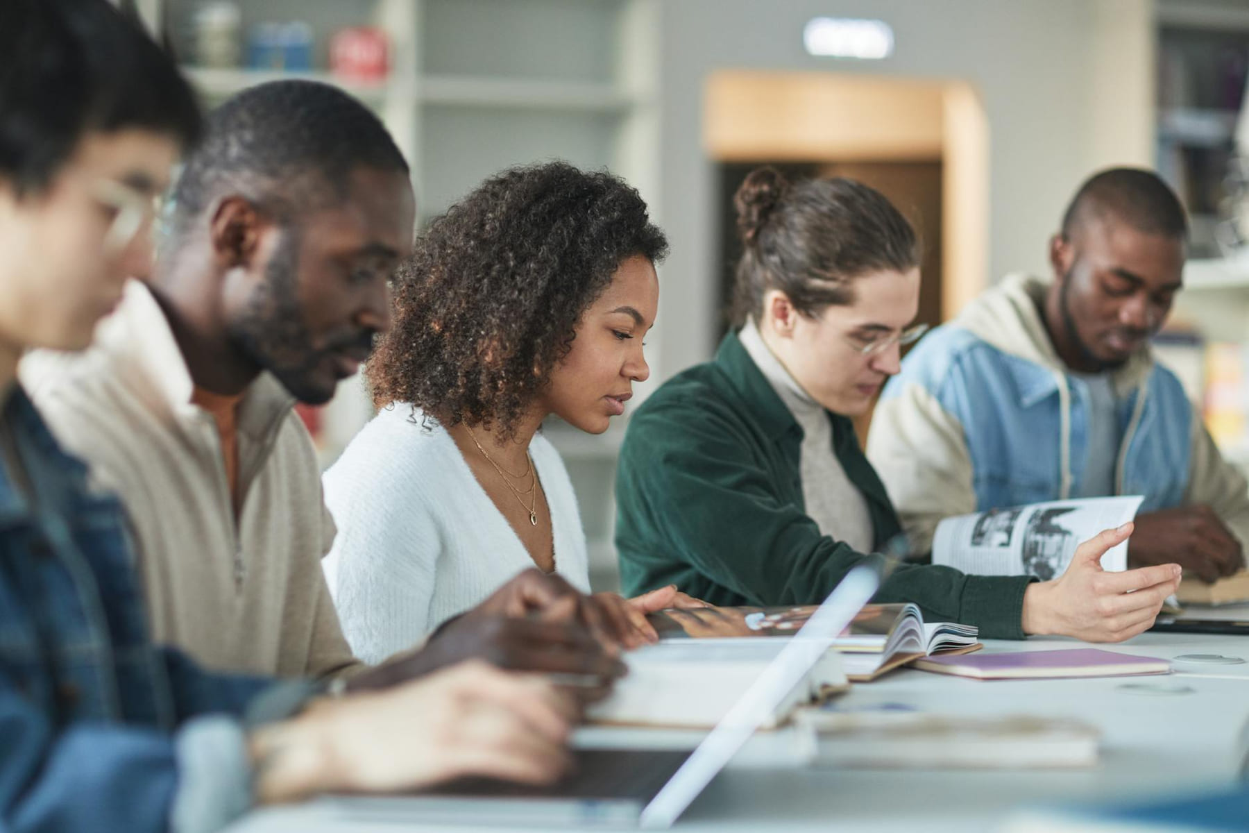 Multiracial group of college students studying together indoors in a library. on The Course Compass
