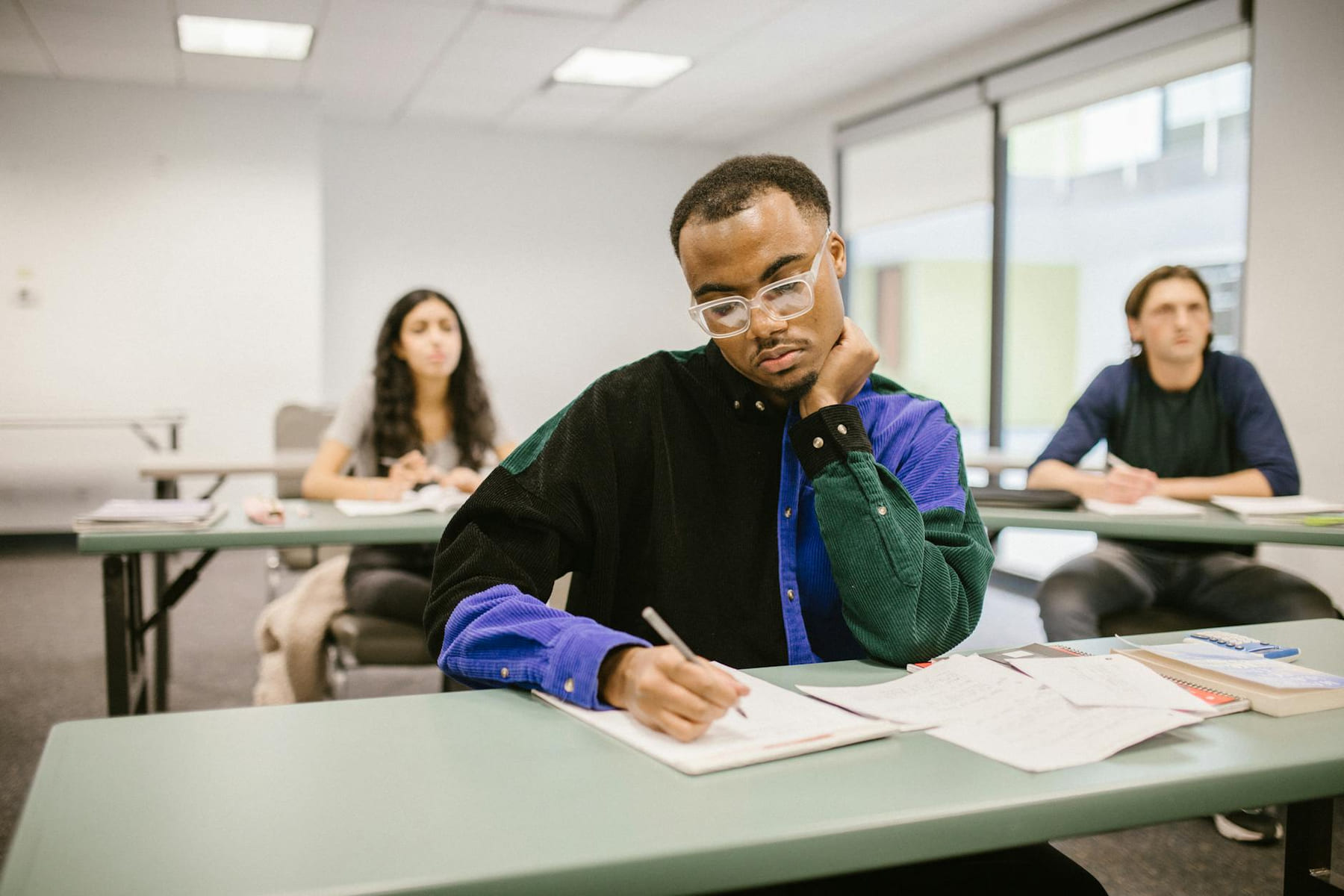 Students in a classroom focusing on their exam papers, depicting diverse educational setting. on The Course Compass