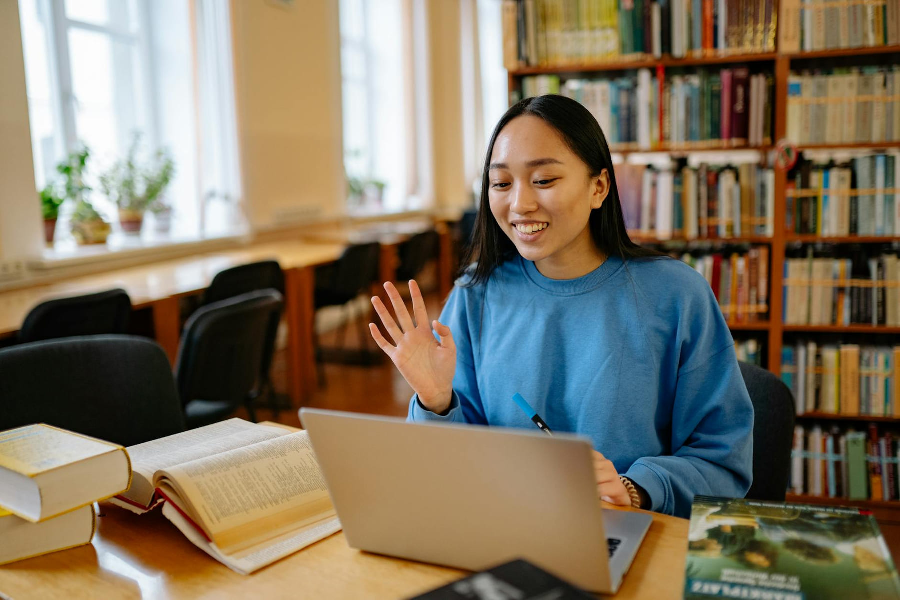 Smiling student using laptop in a library for studying and video calls. on The Course Compass