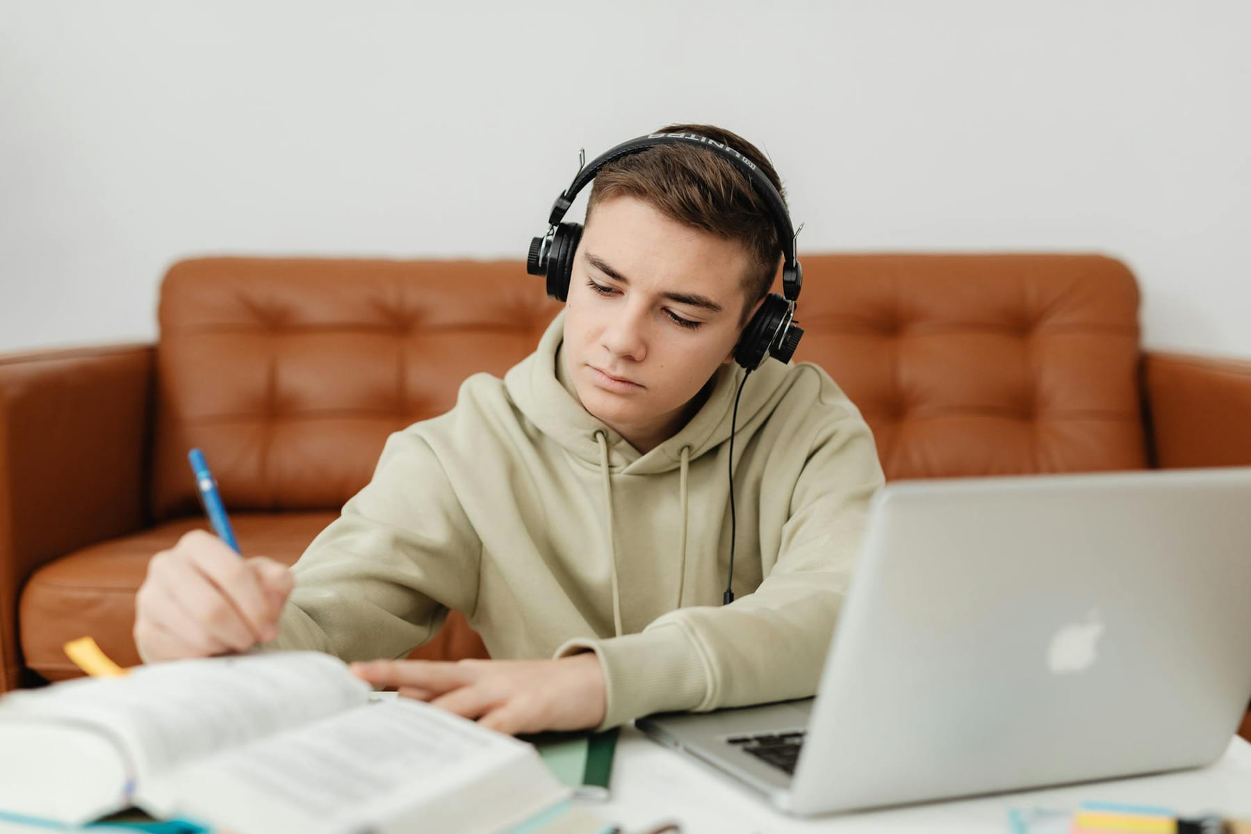 Teenage boy with headphones, focused on studying, using a laptop indoors. on The Course Compass